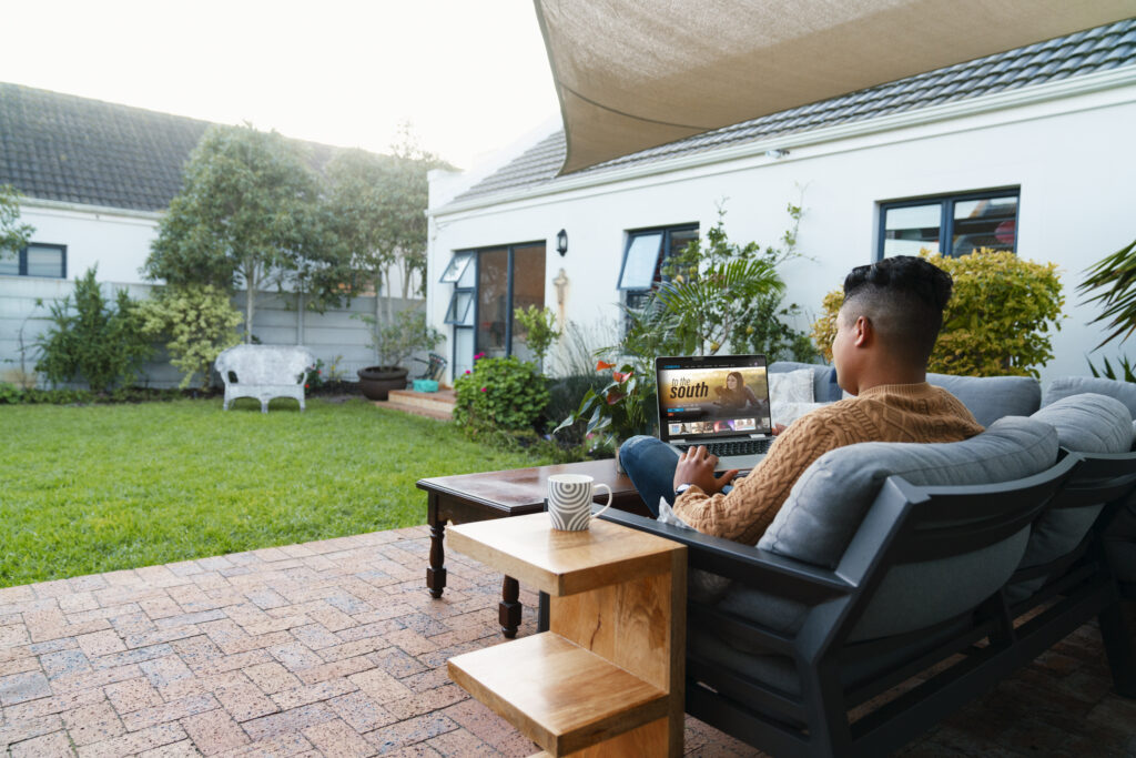 Homeowner relaxing in a professionally designed backyard patio space, showcasing outdoor living features and landscaping as part of a custom backyard design in Utah
